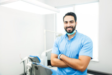 Fototapeta na wymiar Portrait of hadsome dentist doctor wears blue uniform, indoor shot in modern dentist office