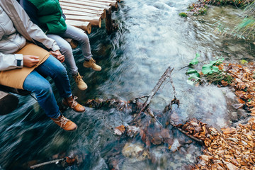 Mother and son sit on the wooden bridge over the mountain stream