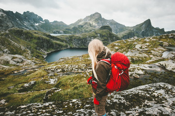 Tourist woman with red backpack hiking in mountains Norway Traveling lifestyle adventure concept...
