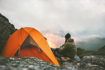 Man traveler relaxing in mountains near of tent camping gear outdoor Travel adventure lifestyle...