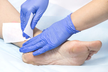 The process of classical wax depilation of female limbs in the beauty salon. 