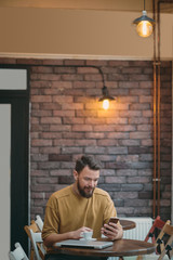 Fototapeta premium Young man sitting in cafe and using smart phone.