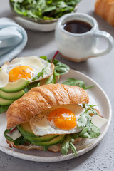 Breakfast with Croissant sandwiches with Fried Egg, Salad Leaves and avocado