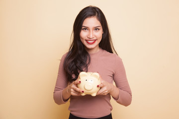 Young Asian woman with a pig coin bank.