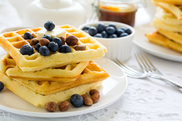 Healthy breakfast. Belgian waffles with butter, blueberry and nuts on white tablecloth. Selective focus