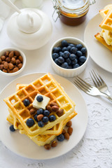 Healthy breakfast. Belgian waffles with butter, blueberry and nuts on white tablecloth. Selective focus