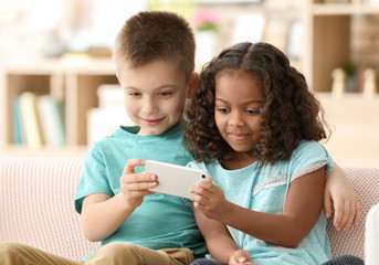 Cute children with smartphone indoors. Child adoption