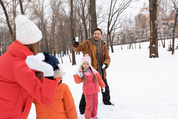 Happy family playing in snowy park on winter vacation