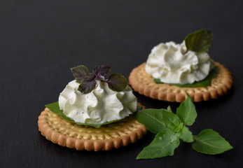 Biscuit cracker appetizer with cream cheese and basil topping
