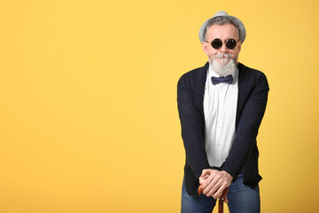 Fototapeta premium Happy senior man in hipster outfit on color background