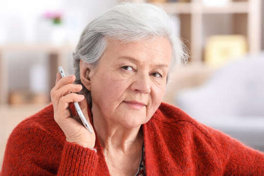 Mature Woman With Hearing Aid Talking On Phone Indoors