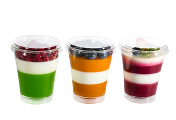 Creamy cream dessert in a plastic cup decorated with berries on a white background. 