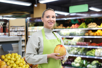 Portrait of young woman with citrus fruit in shop. Small business owner