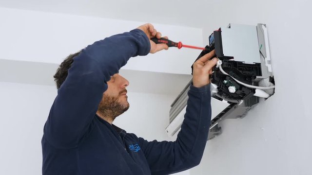 expert technician repairs the air conditioner with screw