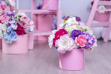 A bouquet of flowers in a basket on the background of floral arrangements in the studio. Beautiful decorations
