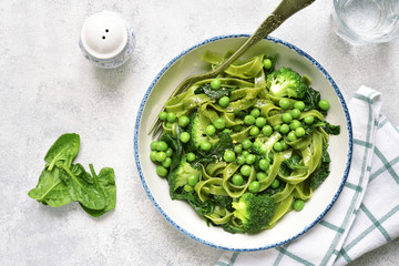 Spinach pasta primavera with green vegetables (broccoli, sweet pea and spinach).Top view.