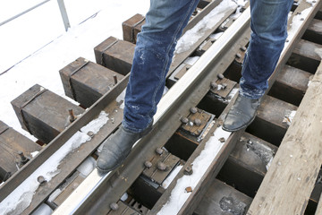 men's legs in jeans and boots are the railway. Walk on the rails. Concept: loneliness, travel, the road of life, a dangerous path.