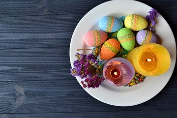 Colorful easter eggs with flowers and candles in the plate. Beautiful easter background. Easter card. Homemade holiday decor.