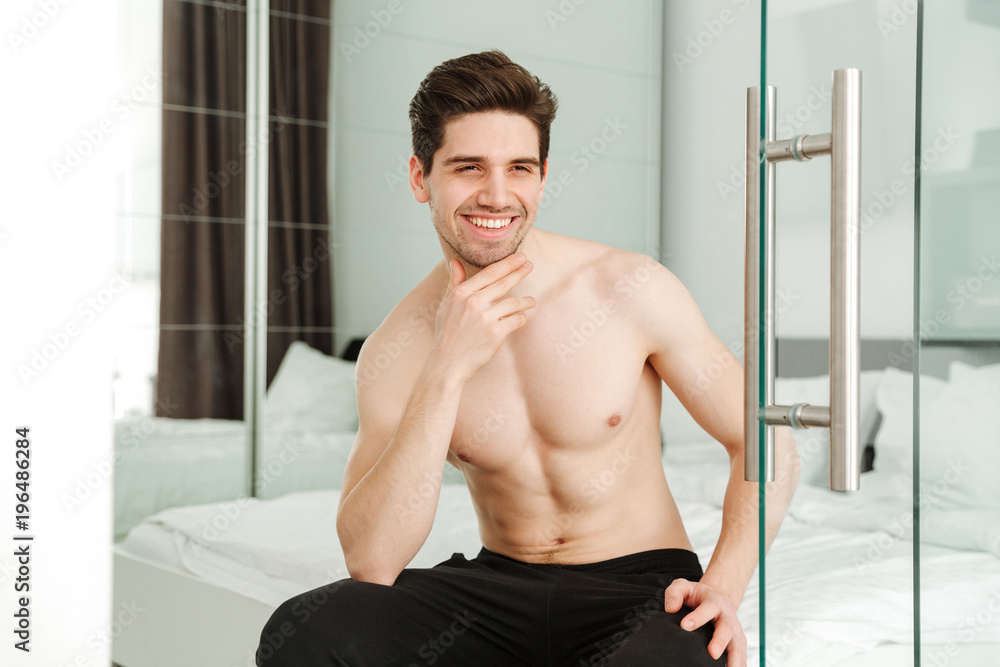 Canvas Prints Happy cheerful naked man sitting on bed