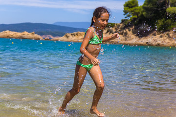 Girl running and splashing on the shallow beach