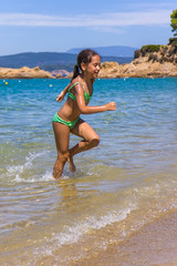 Fototapeta premium Girl running and splashing on the shallow beach