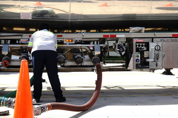 Fuel delivery driver checks the valves as gas is delivered from his tanker to the underground storage tanks at a local gas station.