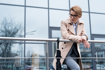 portrait of thoughtful businesswoman in coat standing on street