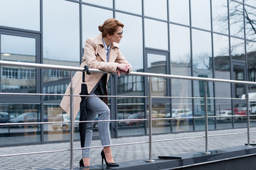 businesswoman in stylish coat standing on street