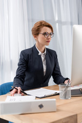 focused businesswoman working at workplace with documents computer screen in office