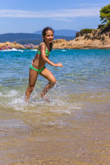 Fototapeta na wymiar Girl running and splashing on the shallow beach