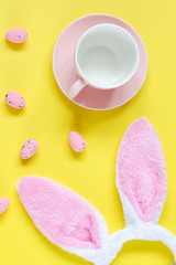 Easter holiday background with empty cup for coffee, bunny ears and easter eggs