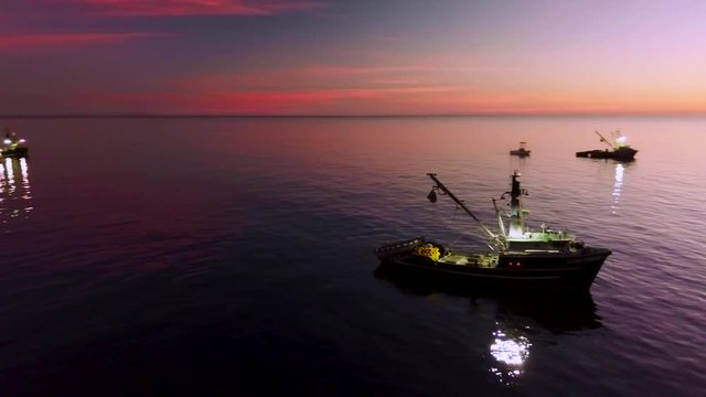 Aerial of squid fishermen with fishing boats lit by bright spotlights off the coast of Malibu, California.
