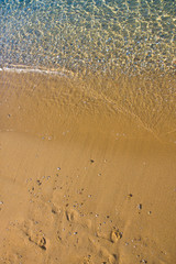Seashore with blue water and orange sand and waves