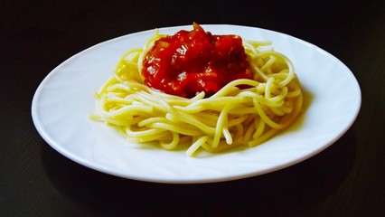 Delicious pasta with vegetables in white plate on black background.
