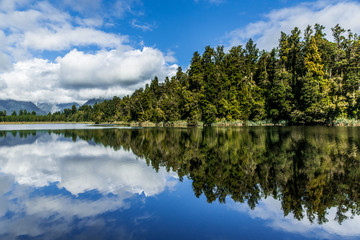 Clean lake mirroring blue sky and green trees