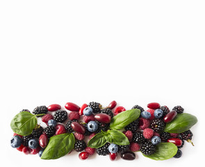 Black-blue and red berries isolated on white. Ripe blackberries, blueberries, raspberries, cornels and basil leaves on white background.  Top view. Background berries.