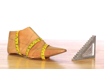 Wooden last shoe with measuring tape on white background