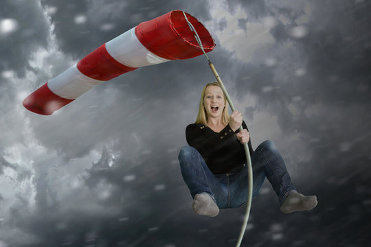 Frau klammert sich bei schlechtem Wetter an einen Windsack