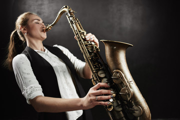 Fototapeta na wymiar Young woman with saxophone on black background