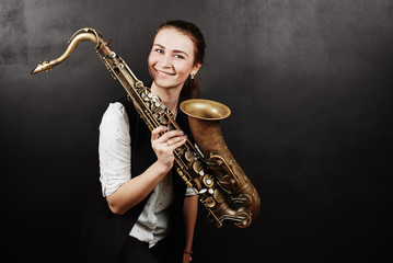 Young woman with saxophone on black background