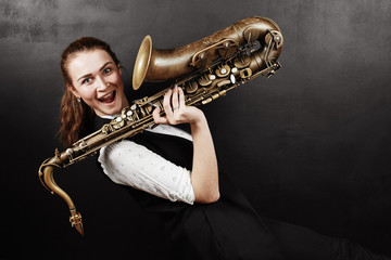 Young woman with saxophone on black background