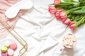 Breakfast in bed pastel flat lay frame composition with flowers, a cup o coffee and sweets. Concept  spring top view