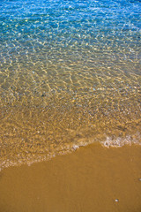 Seashore with blue water and orange sand and waves