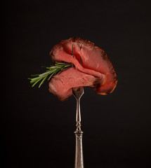 Sliced medium rare grilled roast beef ribeye steak on dark slate kitchen plate background