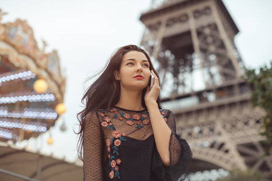 Happy Travel Woman Talking On Phone Near The Eiffel Tower And Carousel, Paris. Portrait Of Travel Tourist Girl On Vacation Walking Happy Outdoors. Attractive Young Romantic Woman In Sexy Black