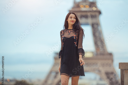 Elegant Romantic Parisian Woman In Black Sexy Dress With Flowers Walking Near The Eiffel Tower