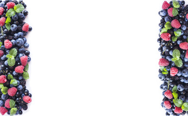 Mix berries and fruits on a white. Berries and fruits at border of image with copy space for text. Ripe blueberries, blackberries, black currants and raspberries on white background. Top view.