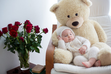 Sweet little baby boy, sleeping with huge teddy bear in big armchair