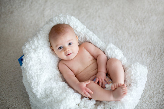 Little baby boy playing at home with soft teddy bear toys