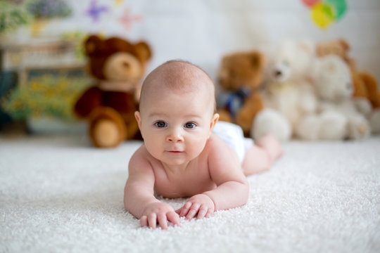 Little baby boy playing at home with soft teddy bear toys